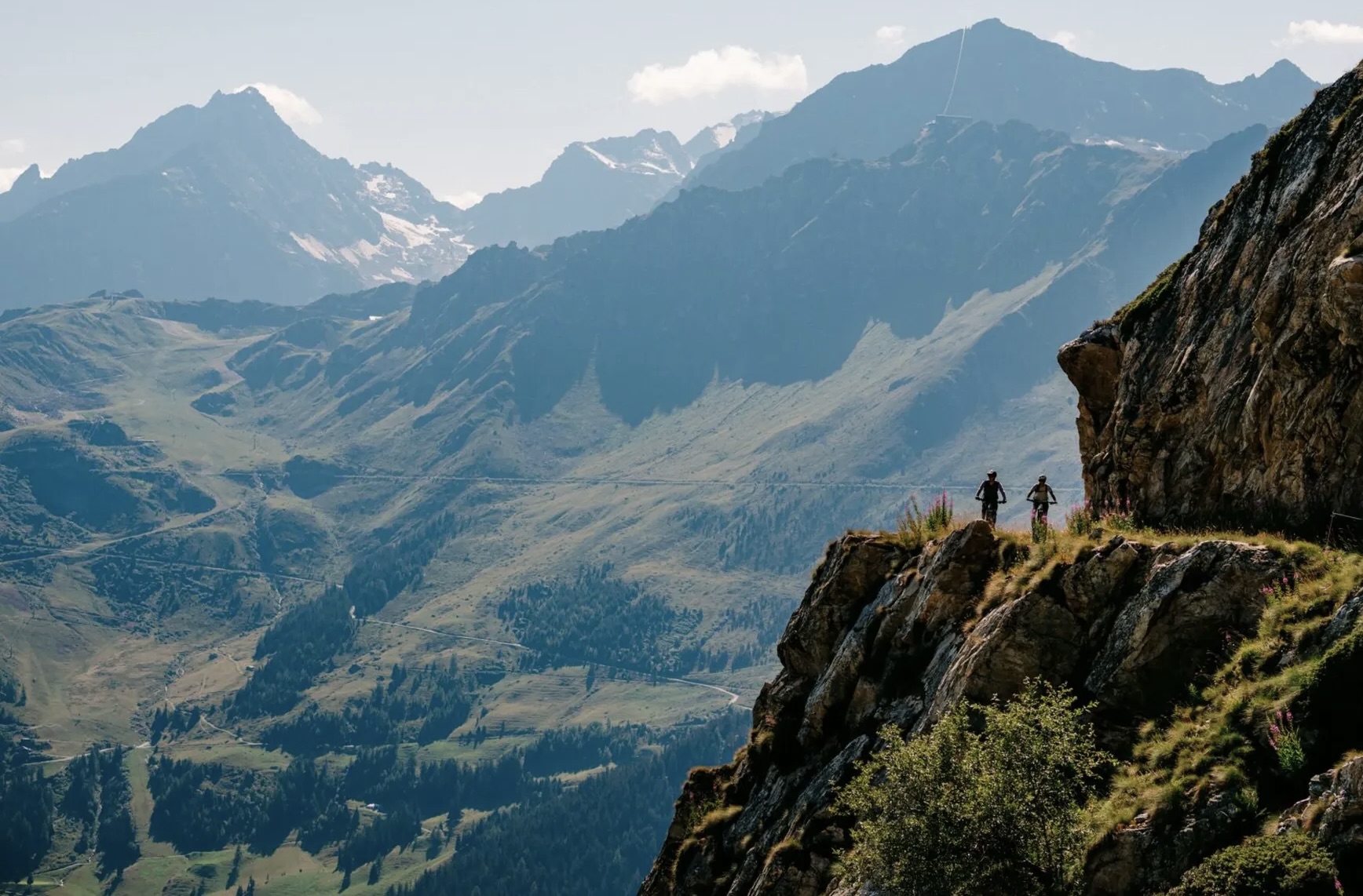 Aerial view of riders on Specialized mountain bikes following an alpine trail near Verbier, surrounded by rugged mountain scenery