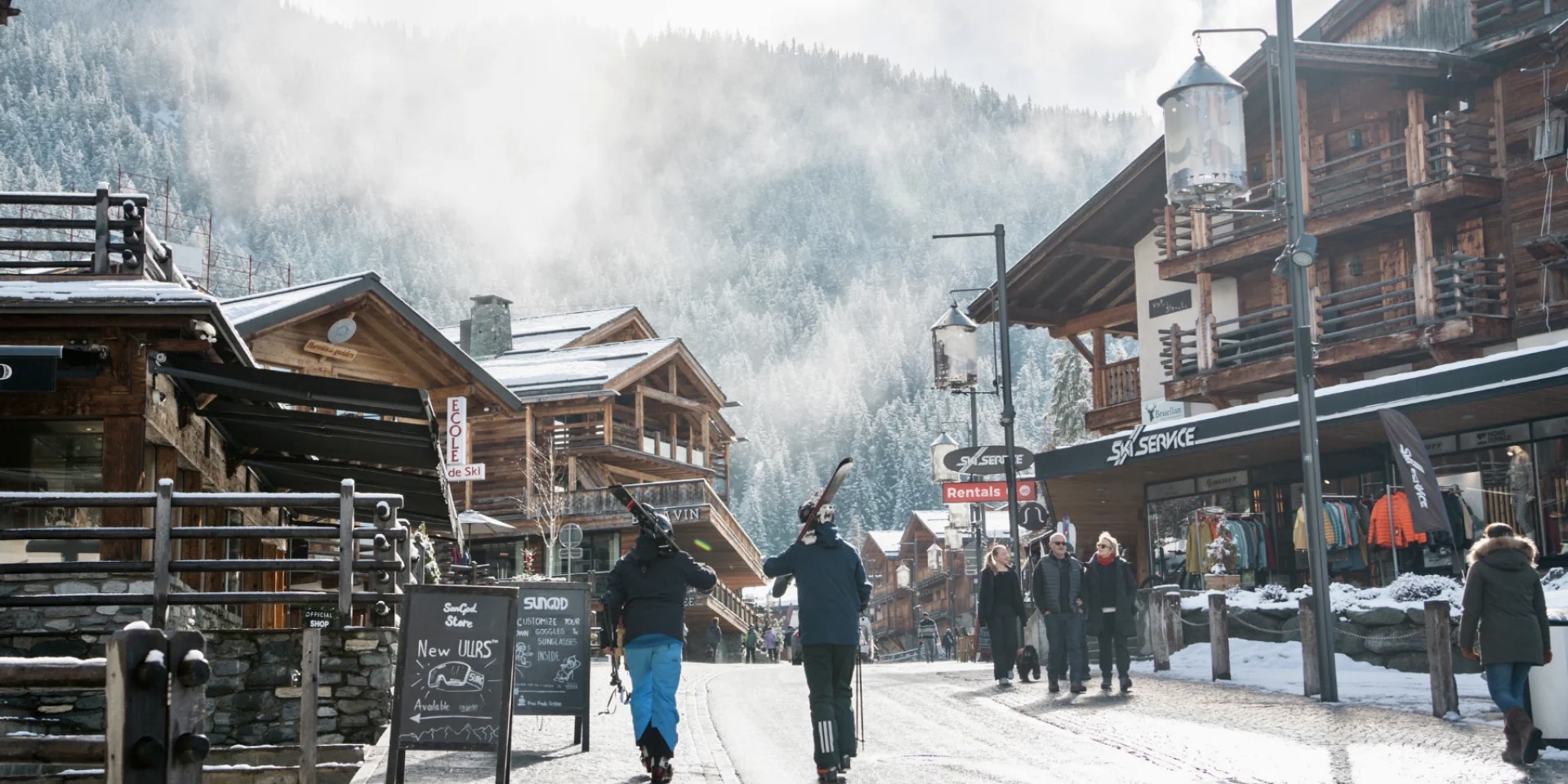 Main street in Verbier with Ski Service shop and people carrying skis